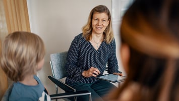Sosiaalityöntekijä katsoo asiakkaita tabletti kädessään