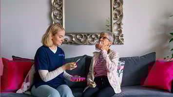 Kotihoidon sairaanhoitaja auttaa vanhusta ottamaan lääkettä