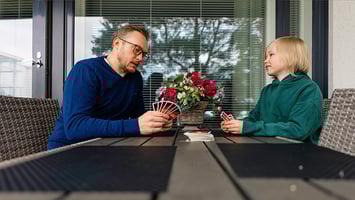 Sosiaalityöntekijä ja lapsi pelaavat Unoa parvekkeella