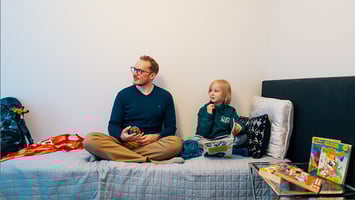 Sosiaalityöntekijä ja lapsi istuvat sängyllä