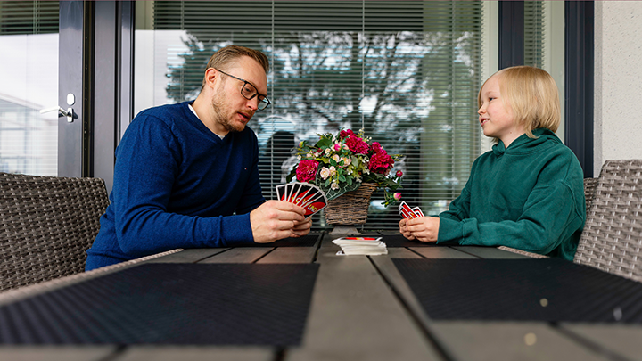 Sosiaalityöntekijä ja lapsi pelaavat Unoa parvekkeella