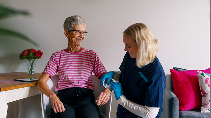 A home care nurse places a bandaid on an elderly woman's arm